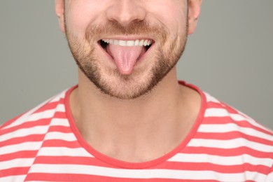 Man showing his tongue on grey background, closeup