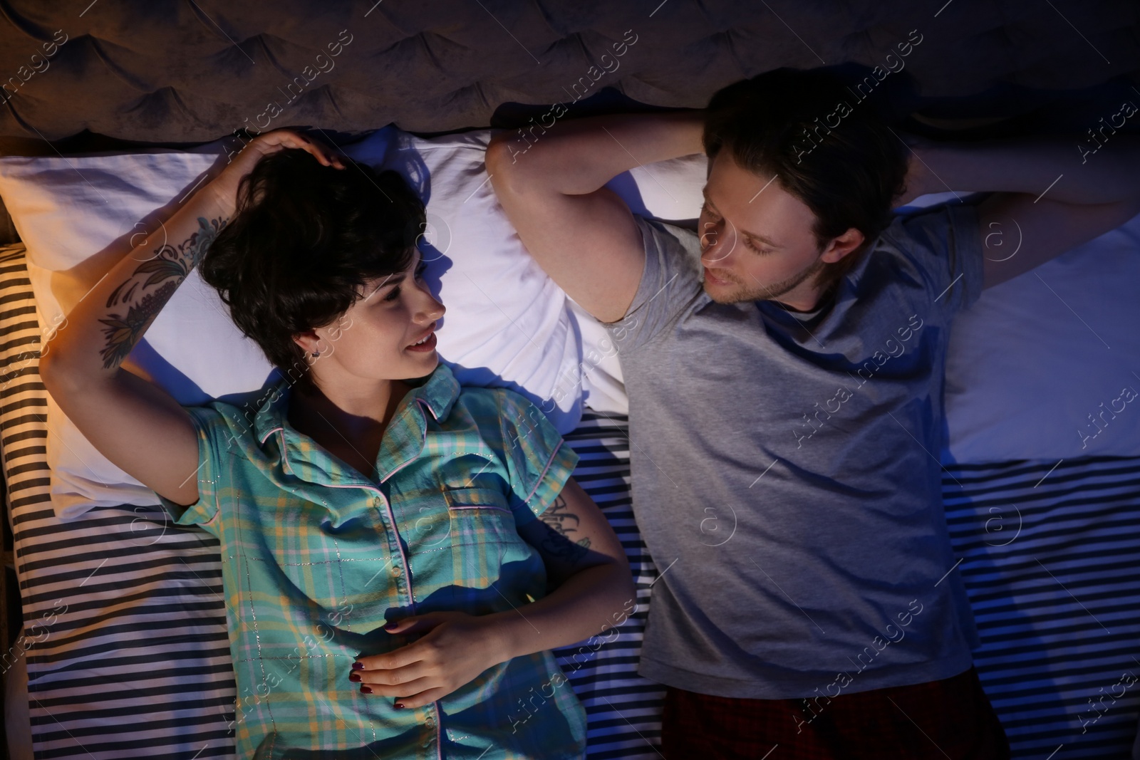 Photo of Young lovely couple lying in bed at night time