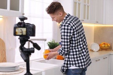 Photo of Smiling food blogger cooking while recording video in kitchen