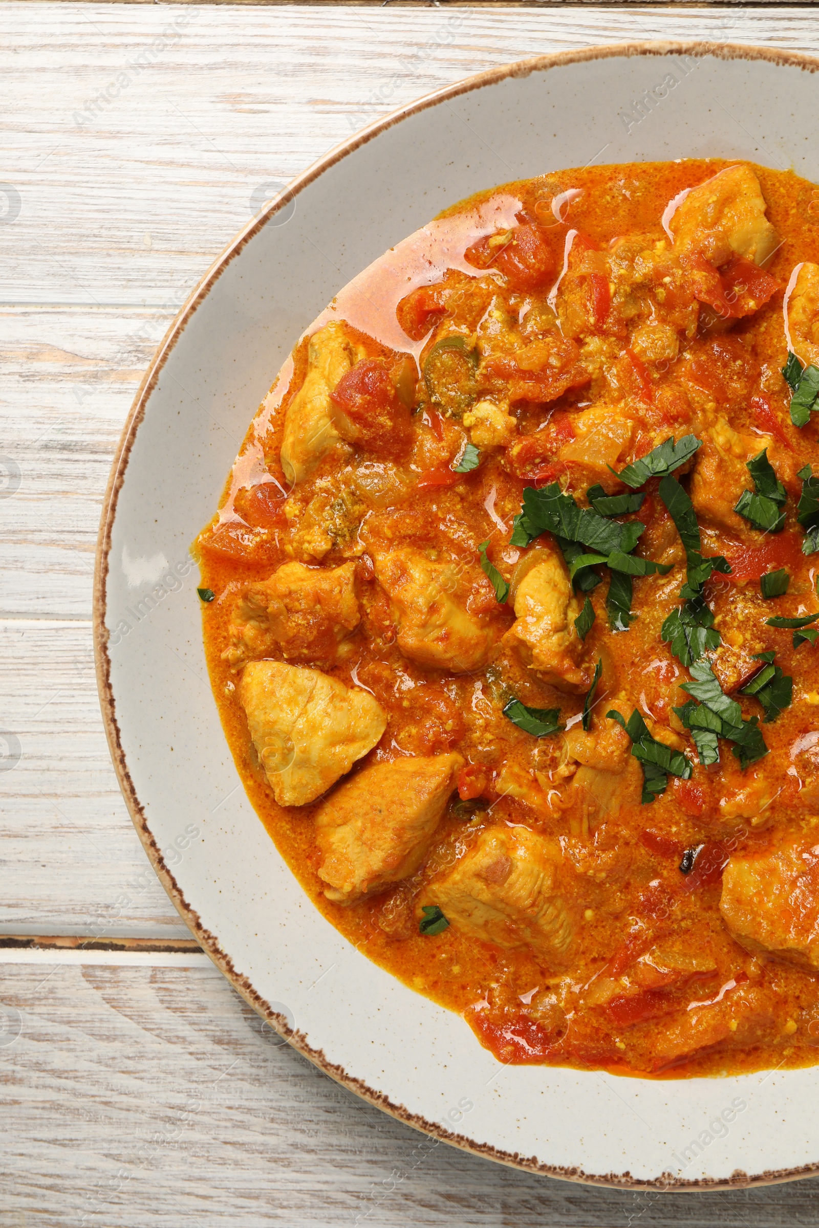 Photo of Delicious chicken curry on wooden table, top view