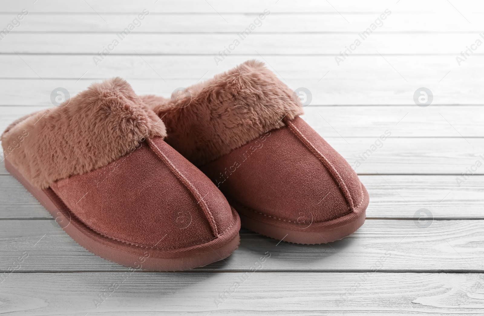 Photo of Pair of stylish soft slippers on white wooden background