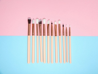 Photo of Flat lay composition with set of professional makeup brushes on color background