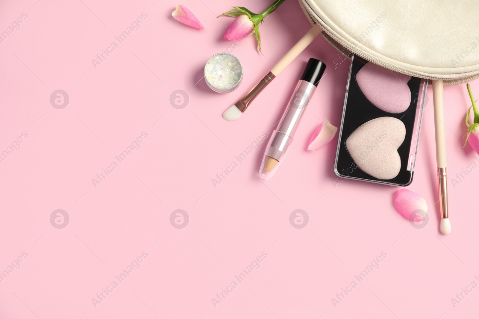 Photo of Set of makeup products with bag and roses on light pink background, flat lay. Space for text