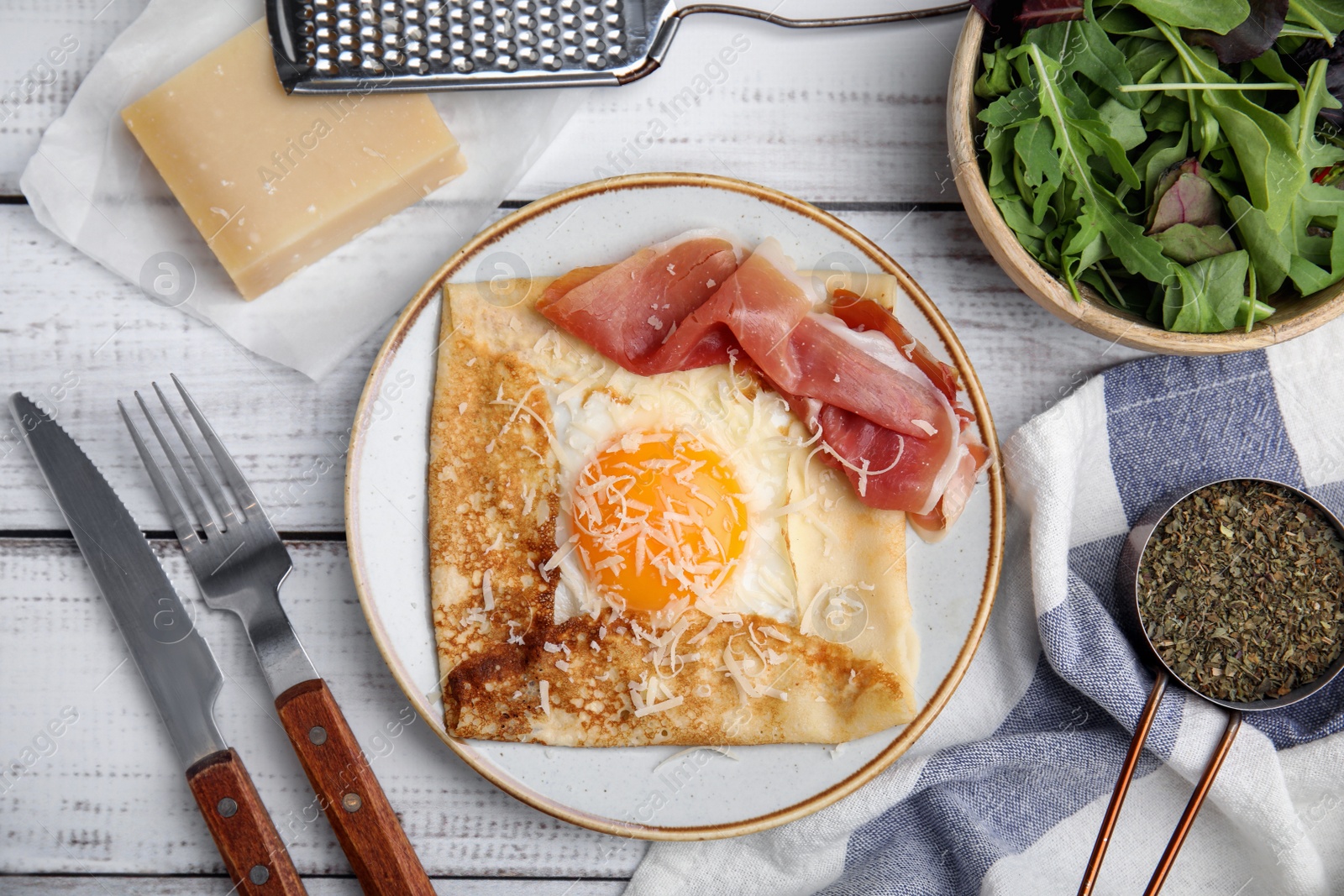 Photo of Delicious crepe with egg served on white wooden table, flat lay. Breton galette