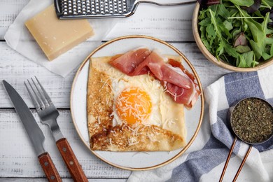 Delicious crepe with egg served on white wooden table, flat lay. Breton galette