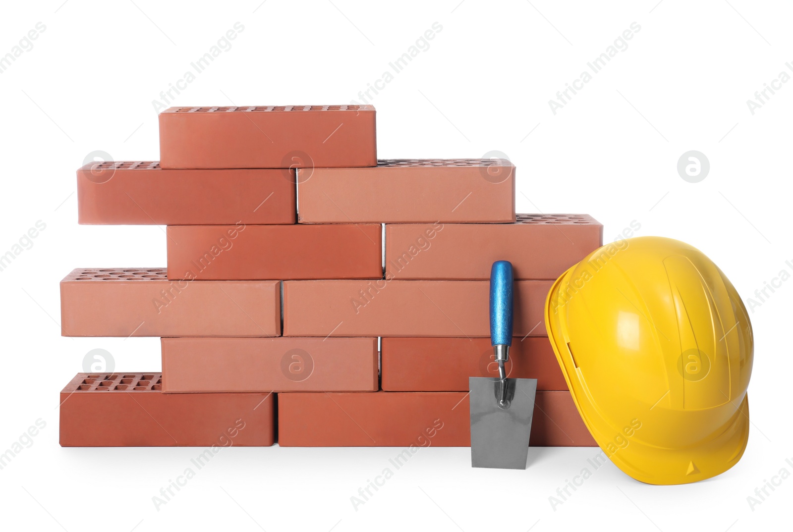 Photo of Many red bricks, hard hat and trowel on white background