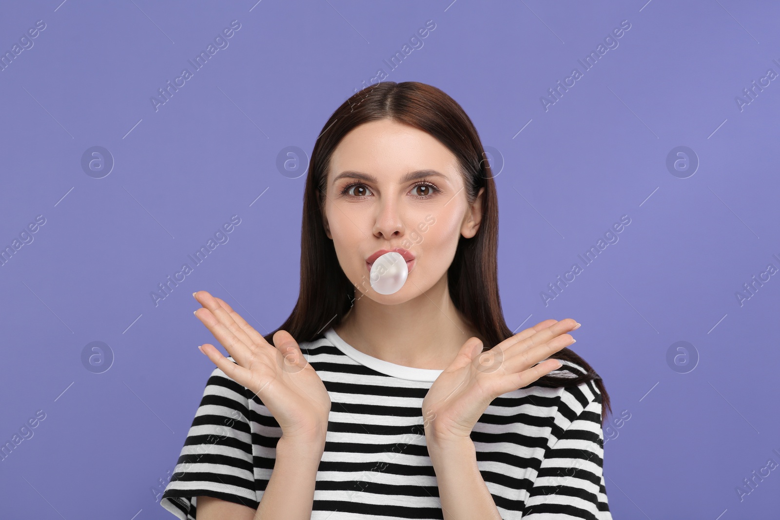 Photo of Beautiful woman blowing bubble gum on light purple background, space for text