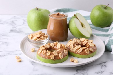 Fresh green apples with peanut butter and nuts on white marble table