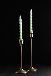 Photo of Vintage metal candlesticks with candles on table against black background