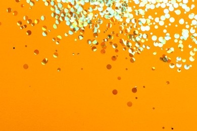 Photo of Shiny bright glitter on orange background, flat lay