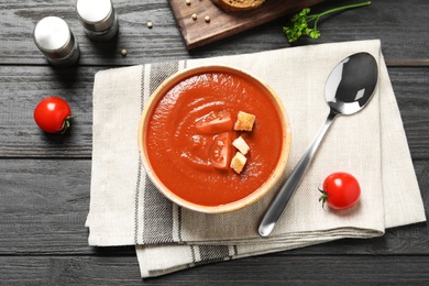 Photo of Bowl with fresh homemade tomato soup on wooden table, top view