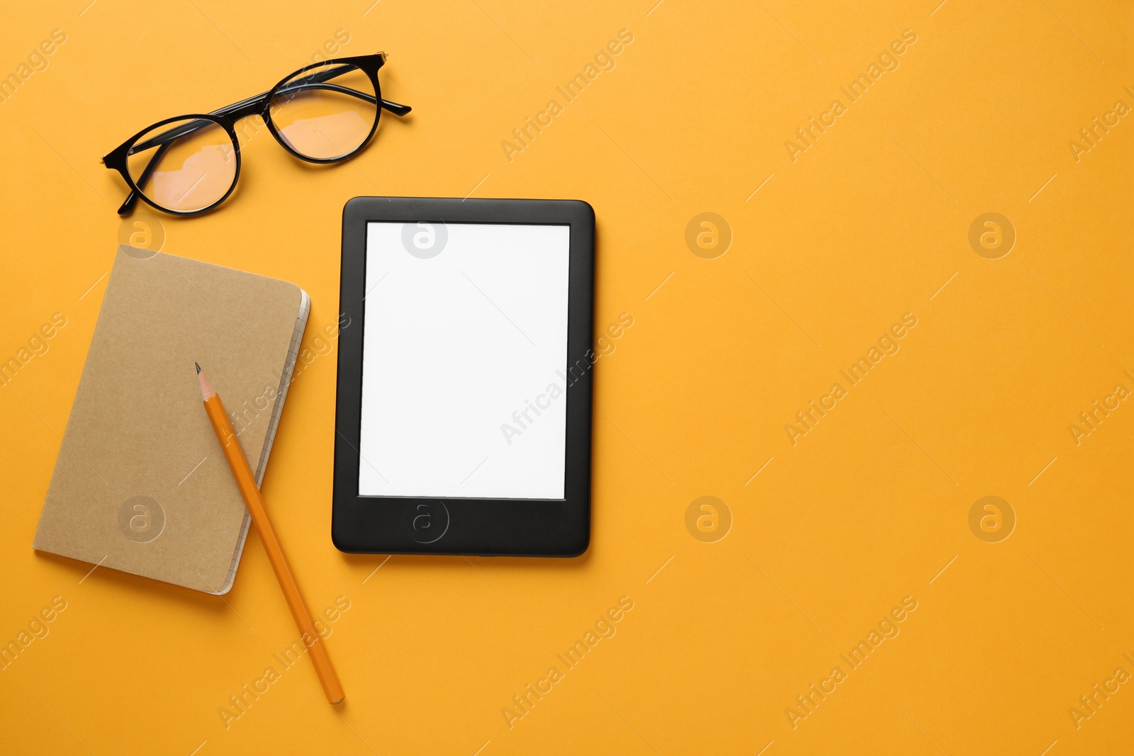 Photo of Modern e-book reader, glasses, notebook and pencil on orange background, flat lay. Space for text