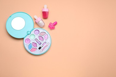 Photo of Children's makeup products and nail polish on pale orange background, flat lay. Space for text