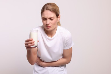Photo of Woman with glass of milk suffering from lactose intolerance on white background, space for text