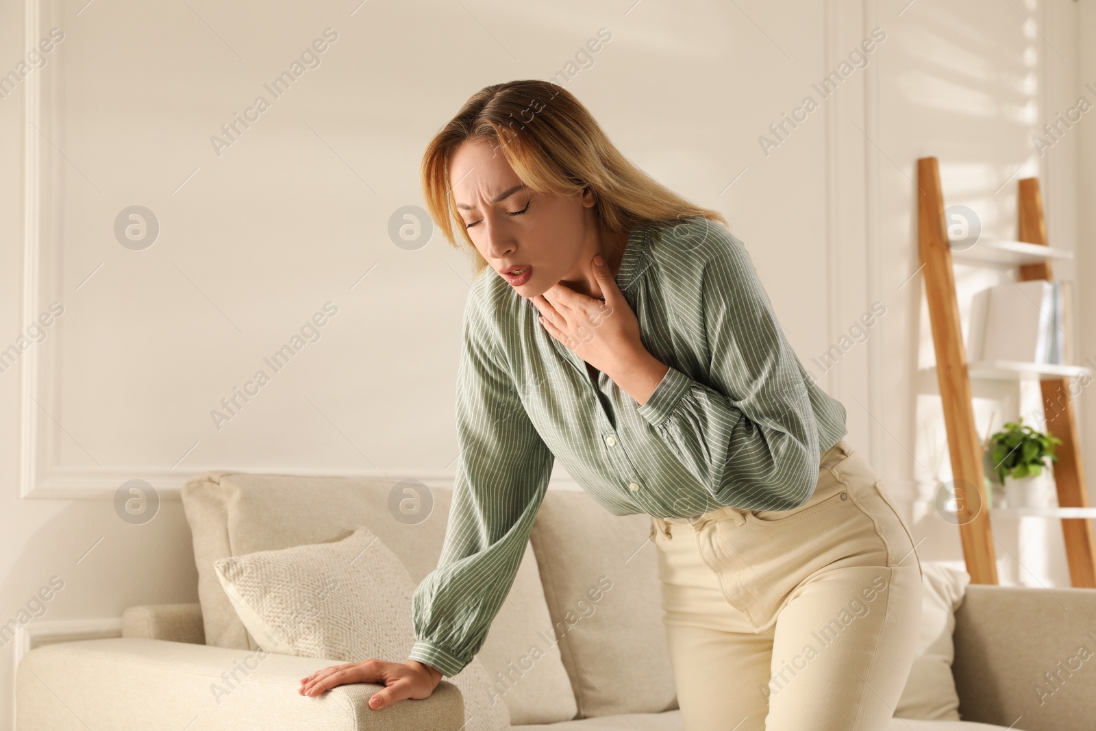 Photo of Young woman suffering from pain during breathing at home