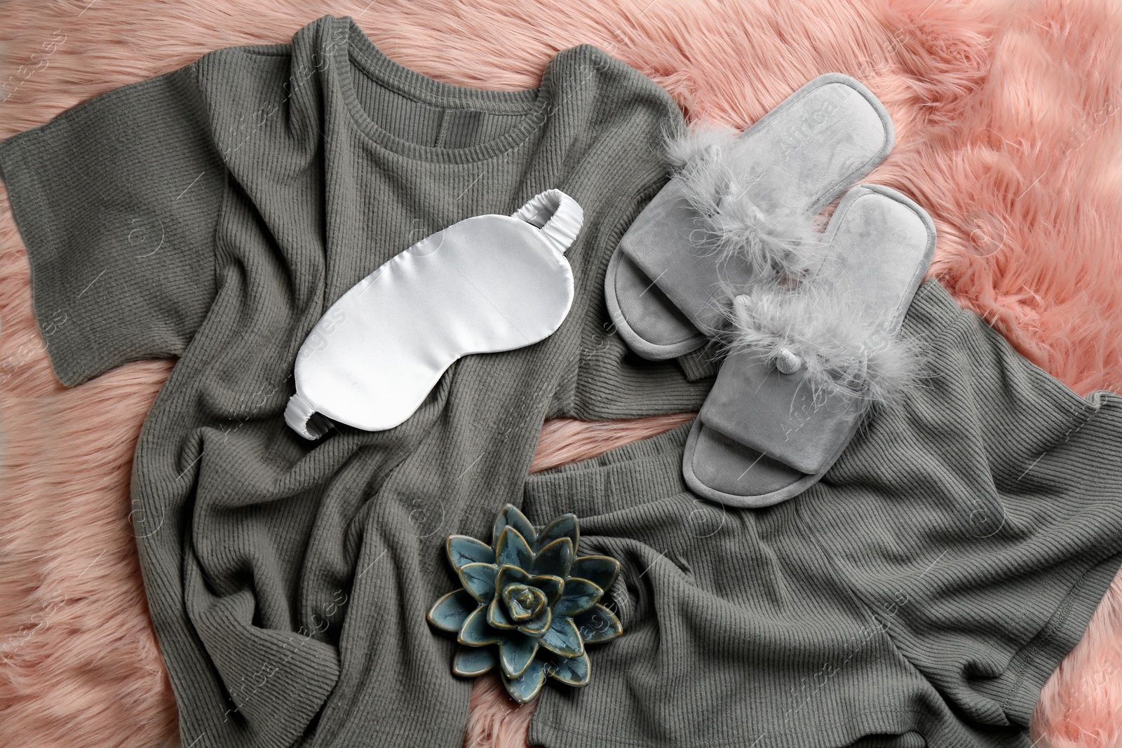 Photo of Pair of fluffy slippers, pajamas and sleeping eye mask on fuzzy carpet, flat lay. Comfortable home outfit