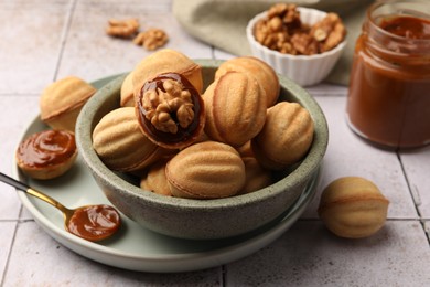 Photo of Delicious nut shaped cookies with boiled condensed milk on light textured table, closeup