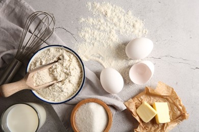 Different ingredients for dough and whisk on light textured table, flat lay