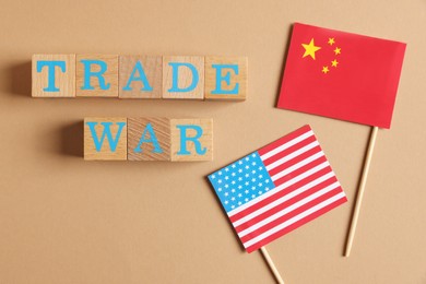 Wooden cubes with words Trade War, American and Chinese flags on beige background, flat lay