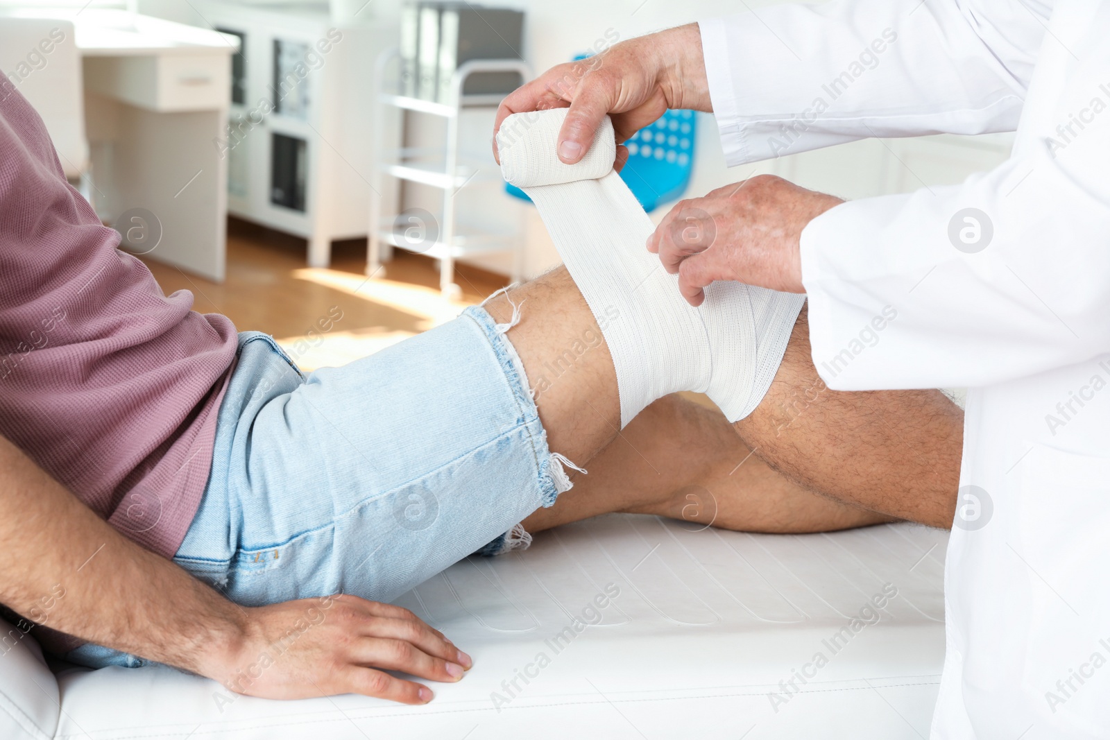 Photo of Doctor applying bandage to patient's knee in clinic, closeup