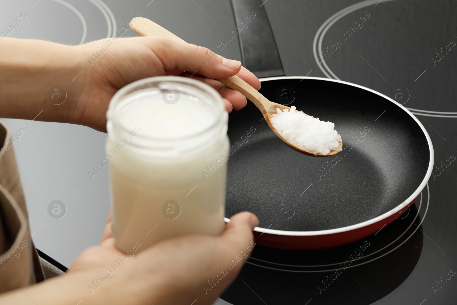 Photo of Woman cooking with coconut oil on induction stove, closeup