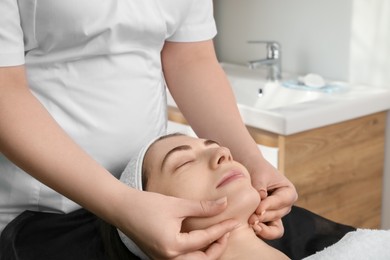 Cosmetologist making face massage to client in clinic, closeup