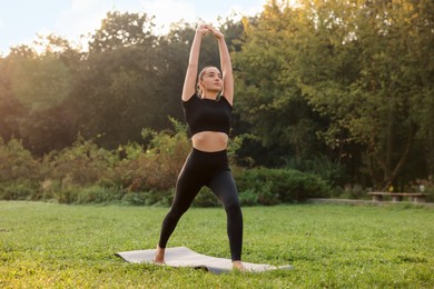 Photo of Beautiful woman practicing yoga on mat outdoors