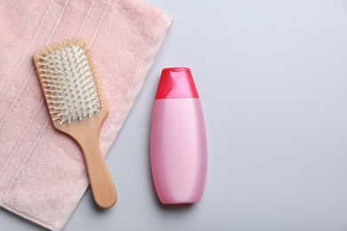 Photo of Bottle with shampoo, towel and brush on color background, flat lay. Space for text