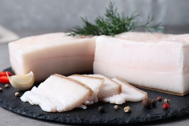 Photo of Pork fatback with spices served on grey table, closeup