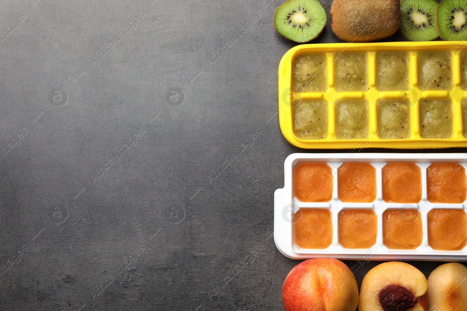 Photo of Nectarine and kiwi puree in ice cube tray with ingredients on grey table, flat lay. Space for text