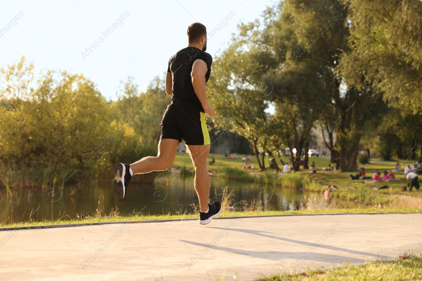 Photo of Man running near pond in park. Space for text