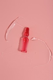 Photo of Skincare ampoule on pink surface with gel, top view