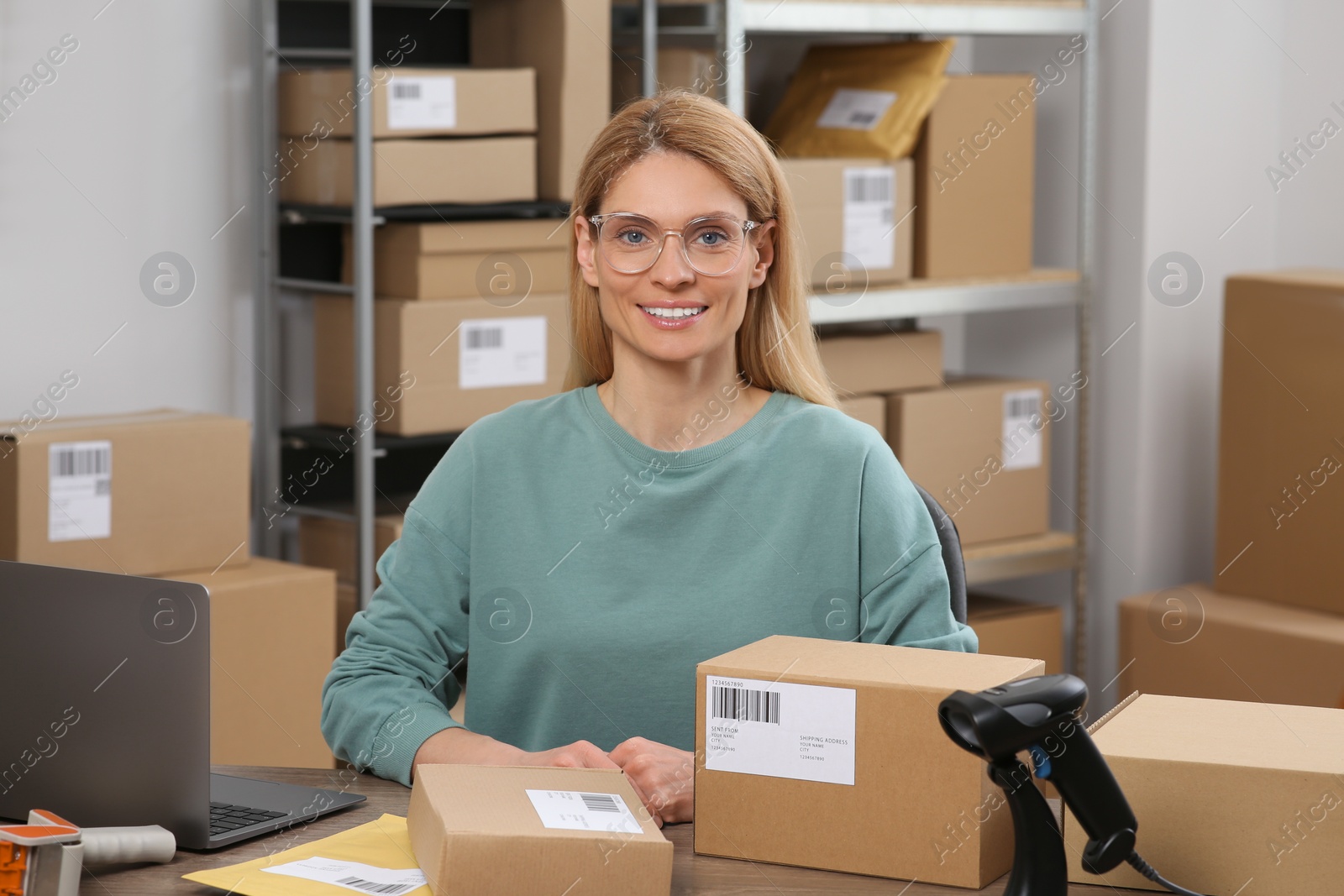 Photo of Seller with parcels and laptop in office. Online store