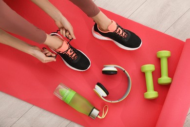 Top view of woman tying shoelaces on yoga mat