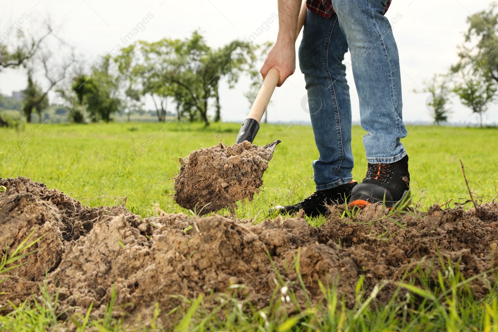 Photo of Worker digging soil with shovel outdoors, closeup