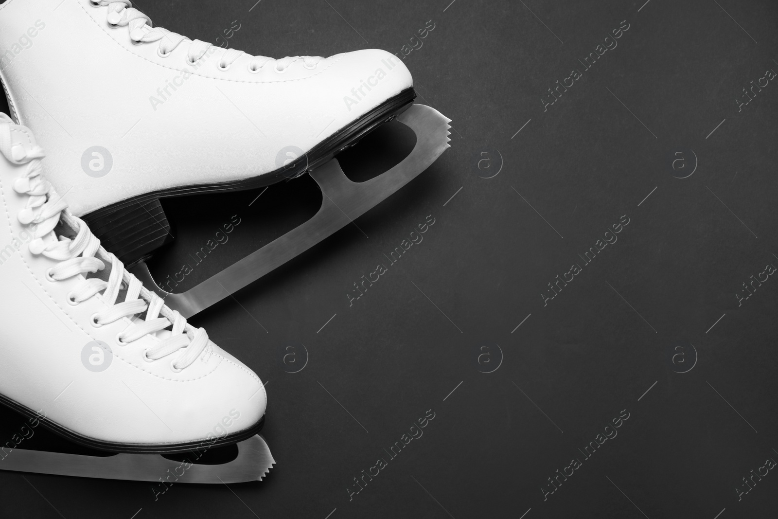 Photo of Pair of skates on black background, above view. Space for text