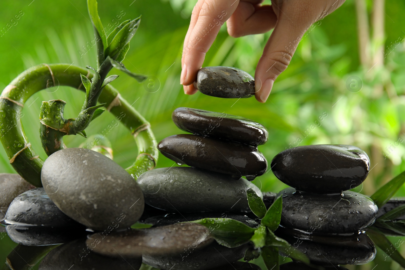 Photo of Woman stacking stones against blurred background, closeup. Zen concept