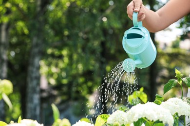 Photo of Woman watering fresh flower bed with can outdoors, closeup. Space for text