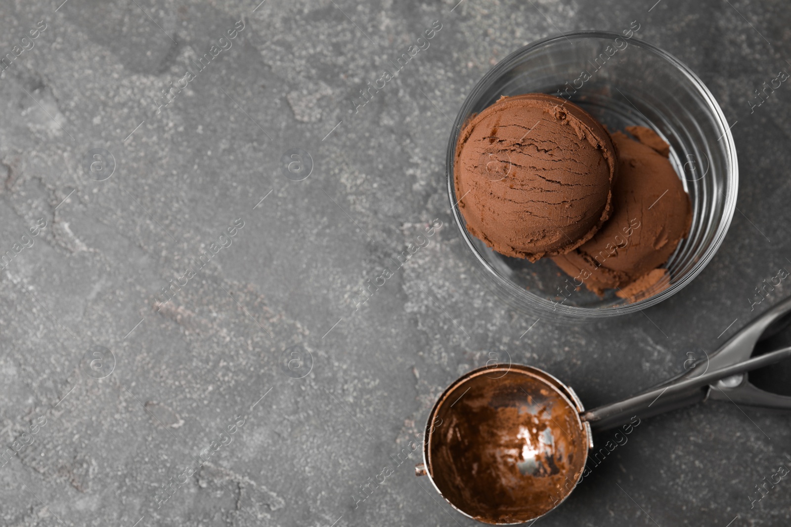 Photo of Glass of chocolate ice cream and scoop on grey table, flat lay. Space for text