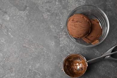 Photo of Glass of chocolate ice cream and scoop on grey table, flat lay. Space for text