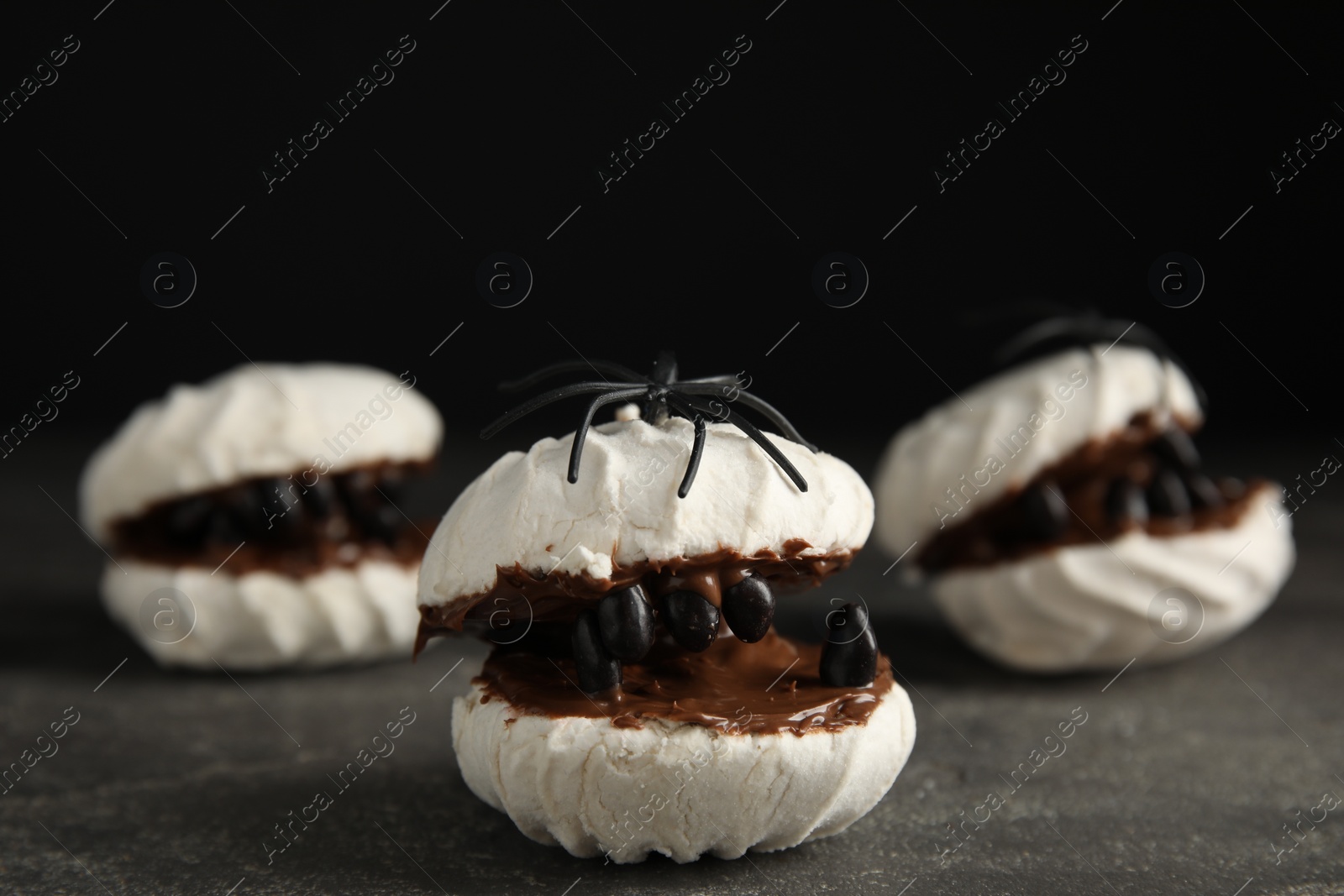 Photo of Delicious desserts decorated as monsters on grey table. Halloween treat