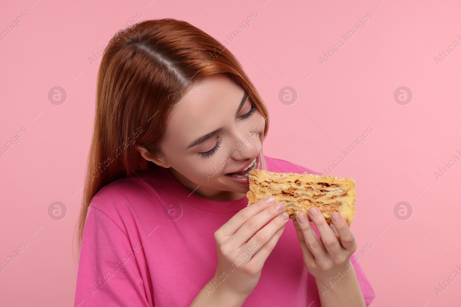 Photo of Young woman eating piece of tasty cake on pink background