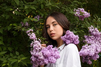 Photo of Attractive young woman near blooming lilac bush outdoors