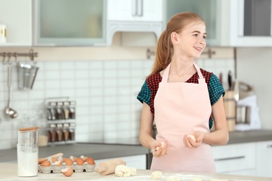 Photo of Teenage girl with raw dough in kitchen