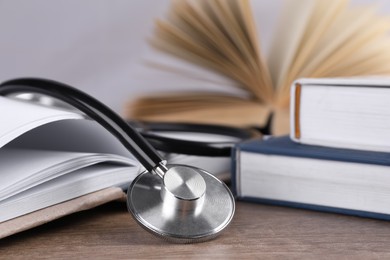 Photo of Student textbooks and stethoscope on wooden table, closeup. Medical education
