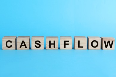 Image of Wooden cubes with phrase Cash FLow on turquoise background