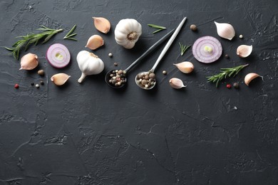 Photo of Fresh raw garlic, onion rings and spices on black table, flat lay. Space for text