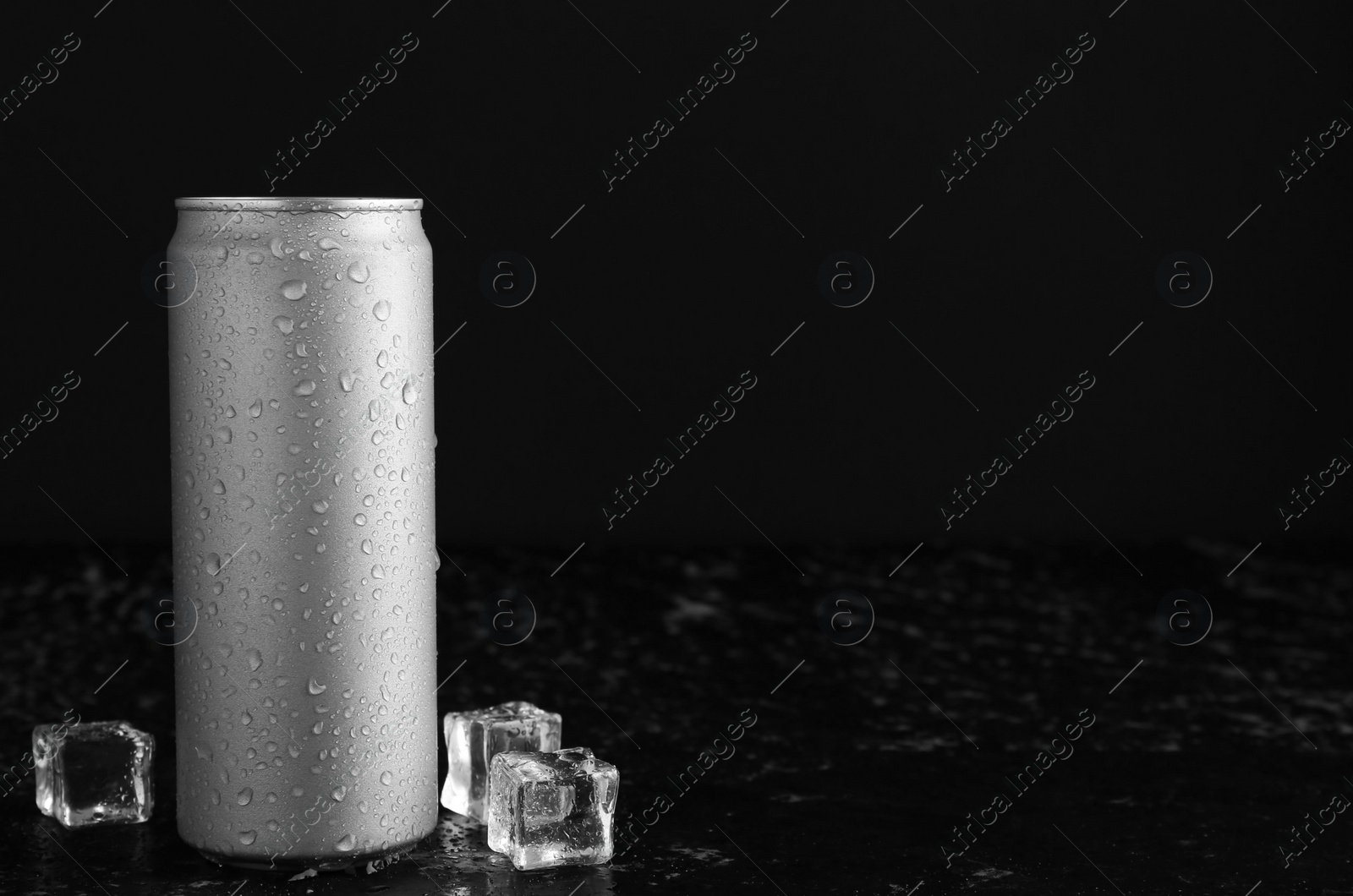 Photo of Energy drink in wet can and ice cubes on black textured table, space for text