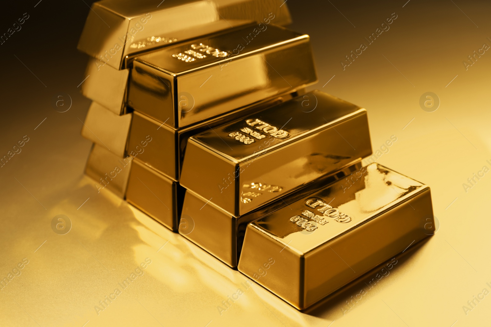 Photo of Stack of shiny gold bars on color background, closeup