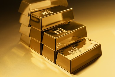Photo of Stack of shiny gold bars on color background, closeup